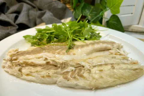 Lubina a la sal jugosa y tierna, servida con una fresca ensalada de rúcula.
