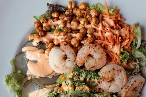 Ensalada fresca con garbanzos crujientes, langostinos jugosos, brócoli, zanahoria rallada y pepinillos encurtidos, todo bañado en una cremosa salsa rosada.