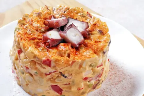Ensaladilla de pulpo cremosa, con trozos de pulpo tierno y pimentón espolvoreado.