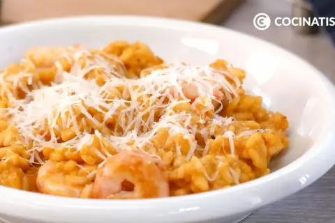 Un cremoso risotto de gambas, cubierto con queso rallado, listo para disfrutar.