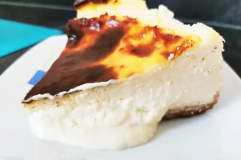 Porción cremosa de tarta de queso con la parte superior dorada y caramelizada, lista para ser disfrutada.