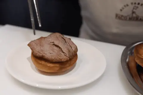 Un delicioso pepito de ternera, jugoso y tierno, listo para ser servido sobre un panecillo.