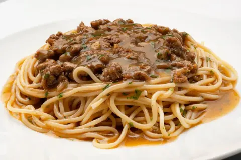 Un plato de espaguetis con una generosa porción de macarrones con carne picada, cubiertos con una sabrosa salsa.