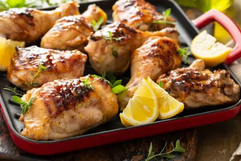 Muslos de pollo dorados y jugosos, asados a la parrilla con hierbas frescas y gajos de limón. ¡Un festín para los sentidos!