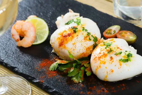 Deliciosa sepia en freidora de aire, servida con gambas, lima y tomates cherry.