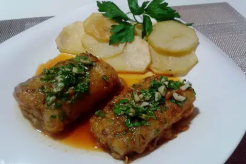 Dos trozos de bacalao a la llauna con patatas y perejil.