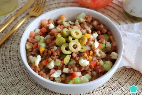 Ensalada de lentejas de bote con tomate, pepino, pimiento y queso fresco, coronada con aceitunas verdes. ¡Un plato fresco y nutritivo!