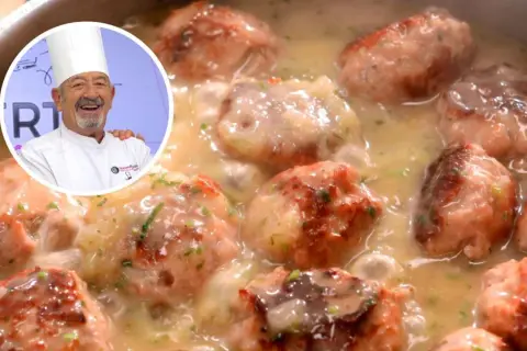 Chef sonriente presenta un plato de albóndigas con patatas en salsa cremosa, decorado con perejil picado.