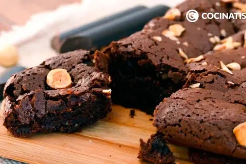 Delicioso brownie sin gluten, con trozos de avellana, sobre una tabla de madera.
