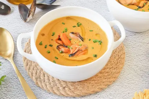 Crema de marisco con mejillones, un delicioso pate de mejillones servido en un cuenco blanco con cebollino y aceite de oliva.