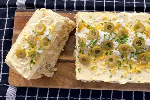 Un delicioso pastel de atún, decorado con aceitunas, huevo rallado y cebollino.