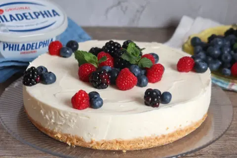 Deliciosa tarta de queso fría cubierta con frambuesas, moras y arándanos frescos. Un postre perfecto para cualquier ocasión.