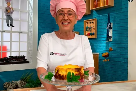 Chef sonriente presenta una deliciosa tarta de queso La Viña, decorada con menta fresca.