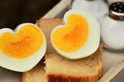 Dos mitades de huevo cocido, con forma de corazón, sobre tostadas. Ideal para saber cuanto tarda en cocer un huevo y disfrutar de un desayuno.