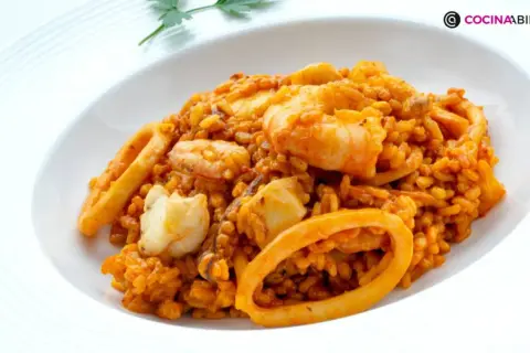 Arroz del senyoret con gambas, calamares y trozos de pescado blanco, servido en un plato blanco.