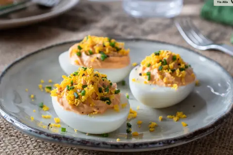 Huevos rellenos de atún, decorados con ralladura de huevo y cebollino. Un aperitivo delicioso y fácil de preparar.
