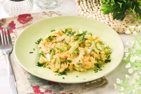 Revuelto de ajetes con perejil fresco, servido en un plato verde claro. Un desayuno ligero y sabroso.