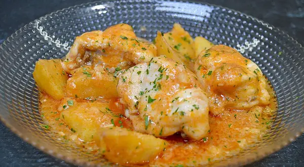 Rape en salsa marinera con patatas, adornado con perejil picado.