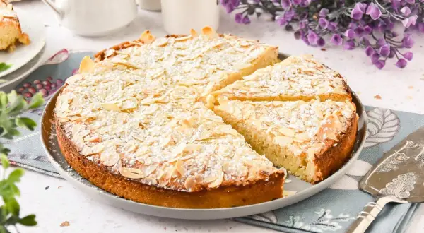 Tarta de almendras dorada y espolvoreada con azúcar glas, lista para servir.