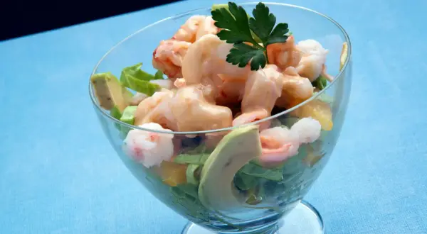 Delicioso coctel de marisco con gambas, aguacate y una cremosa salsa rosa, servido en copa.