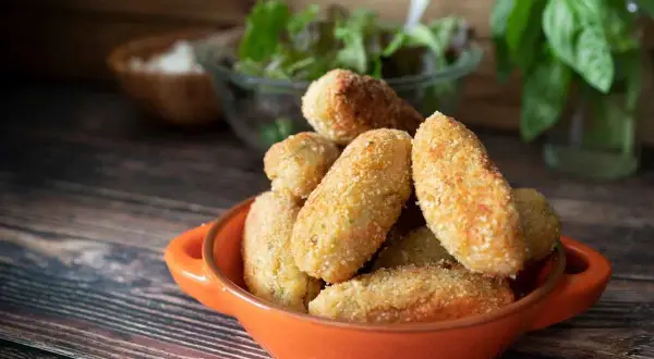 Croquetas de jamón doradas y crujientes en un cuenco naranja, listas para disfrutar.