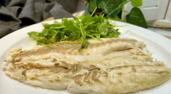 Lubina a la sal jugosa y tierna, servida con una fresca ensalada de rúcula.