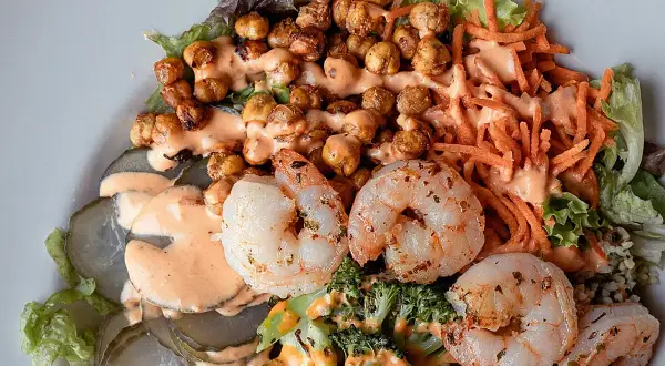 Ensalada fresca con garbanzos crujientes, langostinos jugosos, brócoli, zanahoria rallada y pepinillos encurtidos, todo bañado en una cremosa salsa rosada.