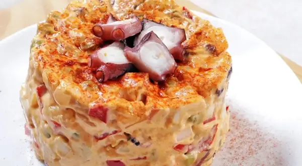 Ensaladilla de pulpo cremosa, con trozos de pulpo tierno y pimentón espolvoreado.