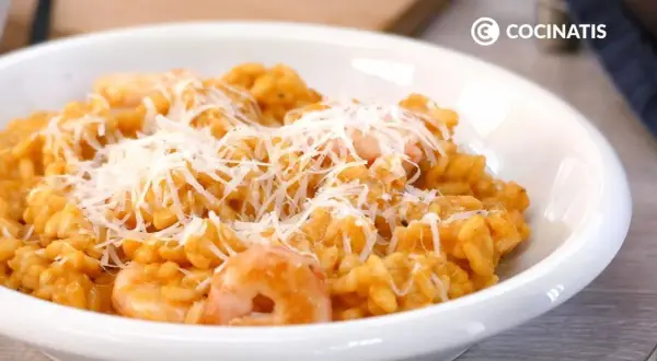 Un cremoso risotto de gambas, cubierto con queso rallado, listo para disfrutar.