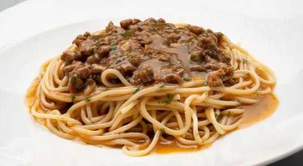 Un plato de espaguetis con una generosa porción de macarrones con carne picada, cubiertos con una sabrosa salsa.