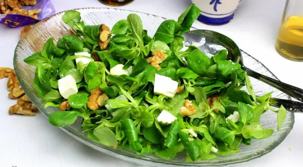Deliciosa ensalada de canonigos con queso fresco y nueces, lista para servir.