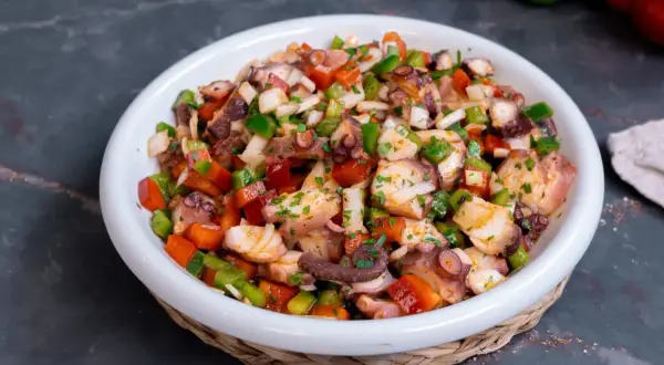 Un refrescante salpicón de pulpo con pimientos, cebolla y perejil, listo para disfrutar.