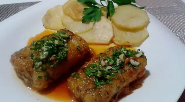 Dos trozos de bacalao a la llauna con patatas y perejil.
