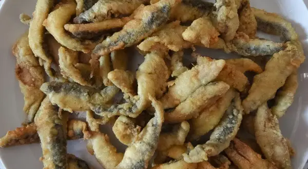 Un plato lleno de boquerones a la andaluza, crujientes y dorados, listos para disfrutar.