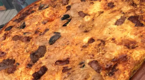 Arroz con costra dorado y crujiente, con trozos de carne y aceitunas negras incrustados.