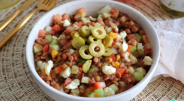 Ensalada de lentejas de bote con tomate, pepino, pimiento y queso fresco, coronada con aceitunas verdes. ¡Un plato fresco y nutritivo!