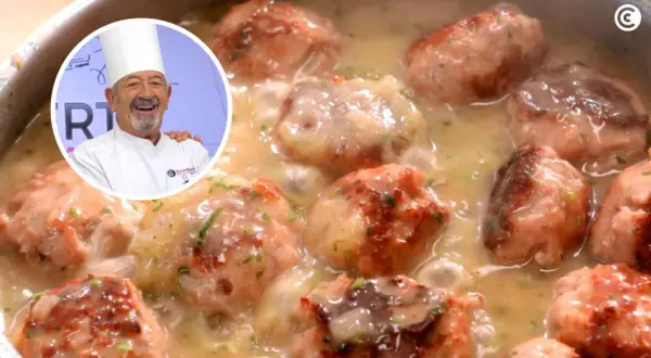 Chef sonriente presenta un plato de albóndigas con patatas en salsa cremosa, decorado con perejil picado.