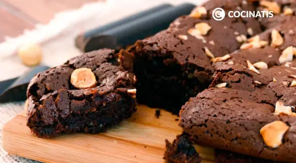 Delicioso brownie sin gluten, con trozos de avellana, sobre una tabla de madera.