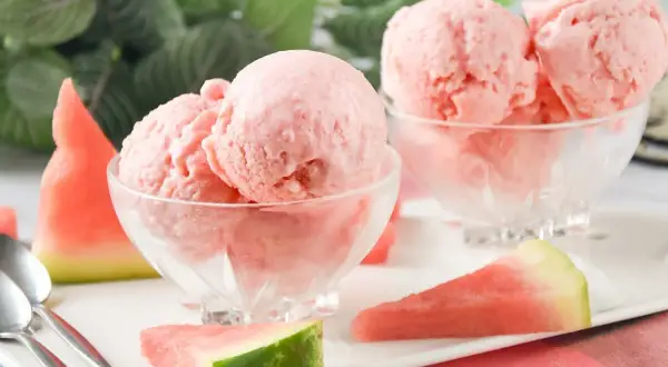 Dos copas de cremoso helado de sandía, decoradas con trozos de fruta fresca. ¡Un postre refrescante!