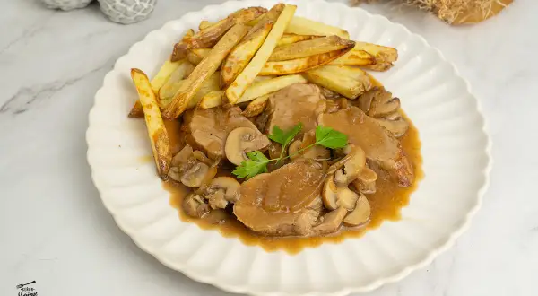 Solomillo en salsa de la abuela con champiñones y patatas fritas. Un plato casero que evoca recuerdos.