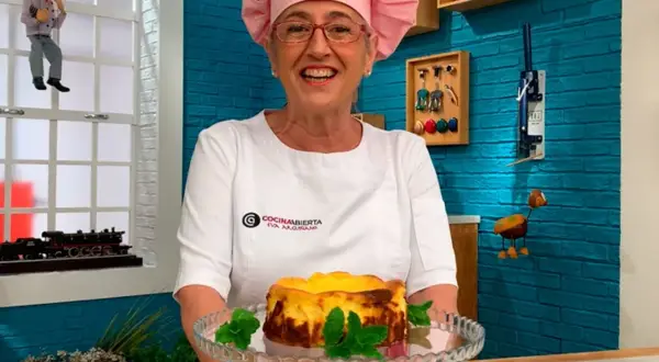 Chef sonriente presenta una deliciosa tarta de queso La Viña, decorada con menta fresca.