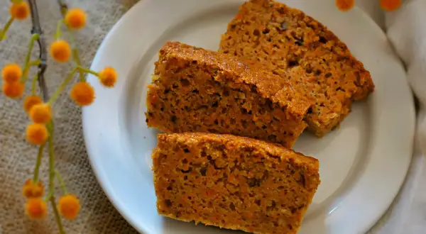 Rebanadas de tarta de zanahoria casera, esponjosas y con trocitos de zanahoria, servidas en un plato blanco.