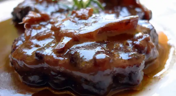 Rabo de ternera estofado, jugoso y tierno, bañado en su propia salsa oscura y aromática, con un toque de romero fresco.