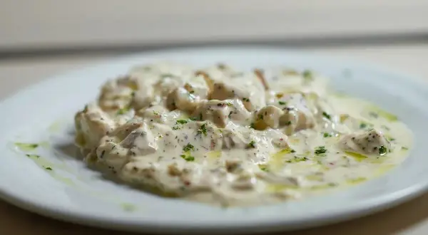 Deliciosa brandada de bacalao cremosa, espolvoreada con perejil fresco y un toque de aceite de oliva.