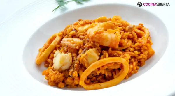 Arroz del senyoret con gambas, calamares y trozos de pescado blanco, servido en un plato blanco.