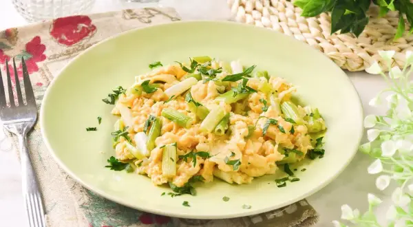 Revuelto de ajetes con perejil fresco, servido en un plato verde claro. Un desayuno ligero y sabroso.