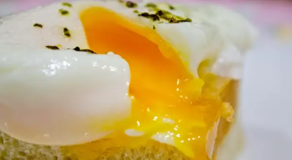 Un huevo poche microondas perfecto, con la clara cuajada y la yema líquida, servido sobre una tostada.