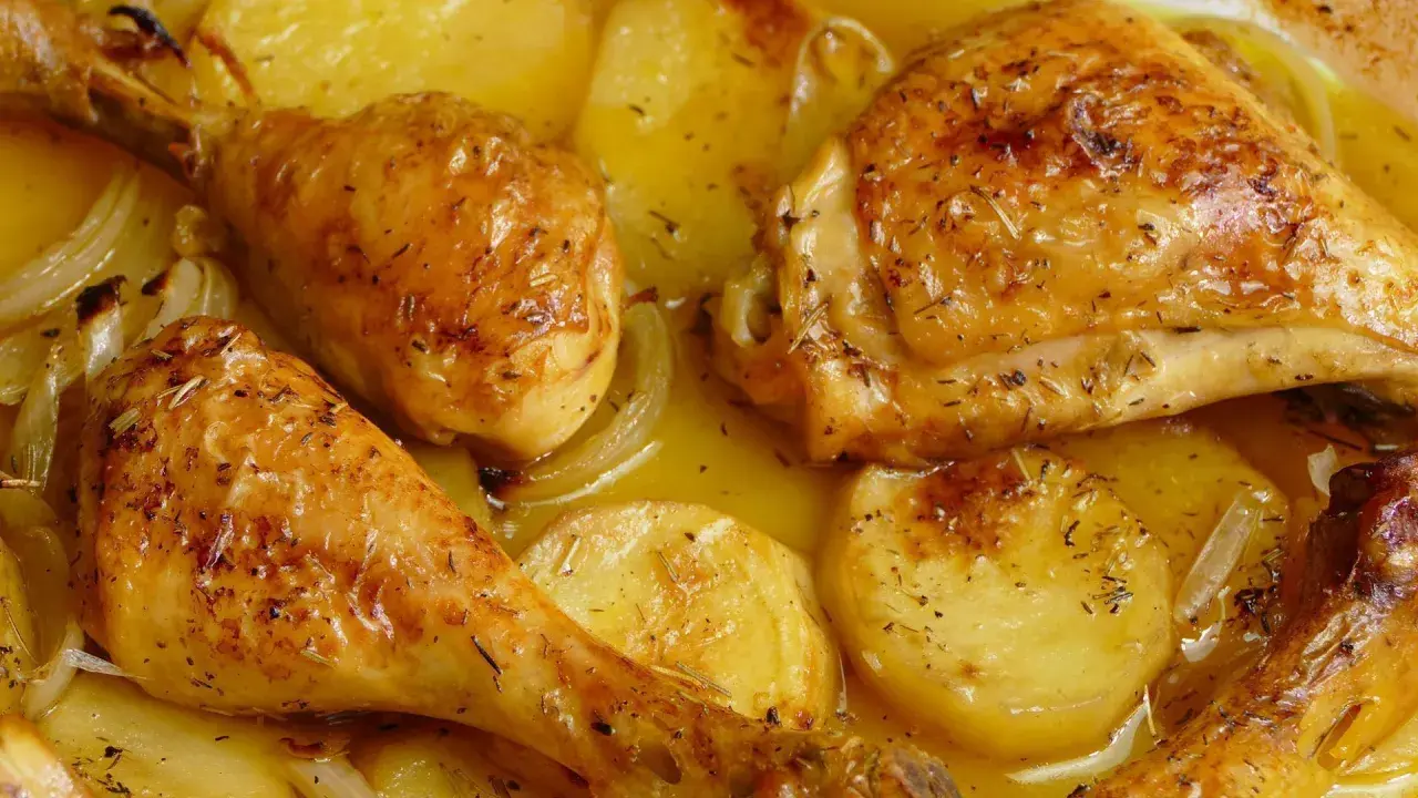 Pollo al horno con patatas y cebolla, dorado y jugoso, con hierbas aromáticas. Un plato casero irresistible.