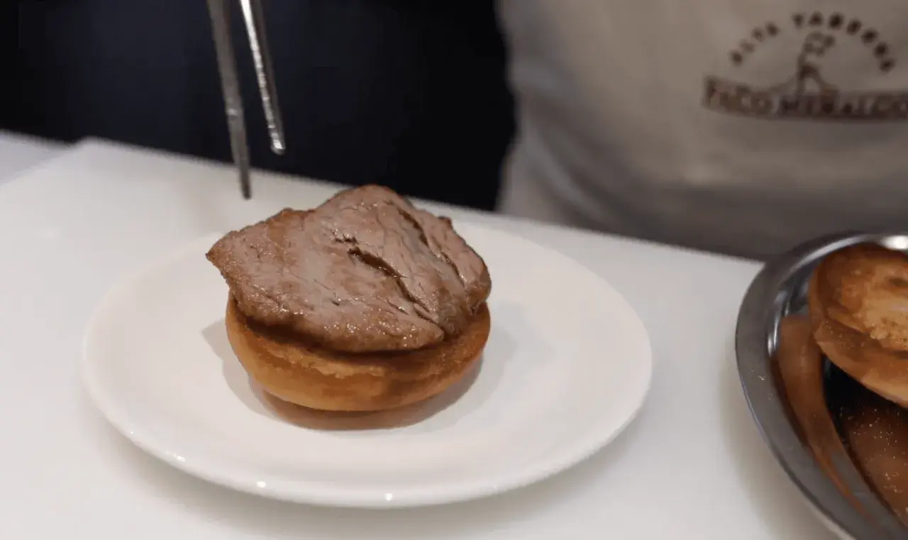 Un delicioso pepito de ternera, jugoso y tierno, listo para ser servido sobre un panecillo.