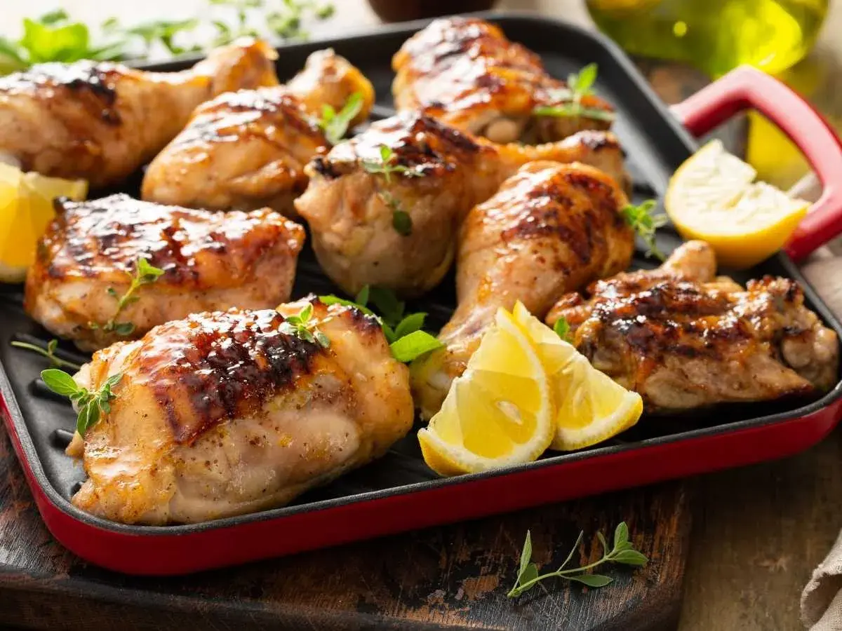 Muslos de pollo dorados y jugosos, asados a la parrilla con hierbas frescas y gajos de limón. ¡Un festín para los sentidos!